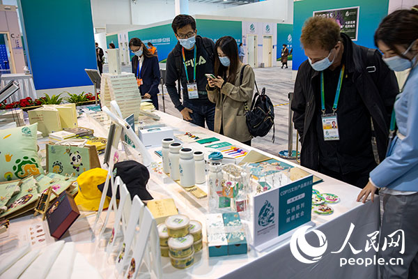 COP15参会嘉宾在陈列桌前浏览环保文创产品。（人民网记者 翁奇羽摄）