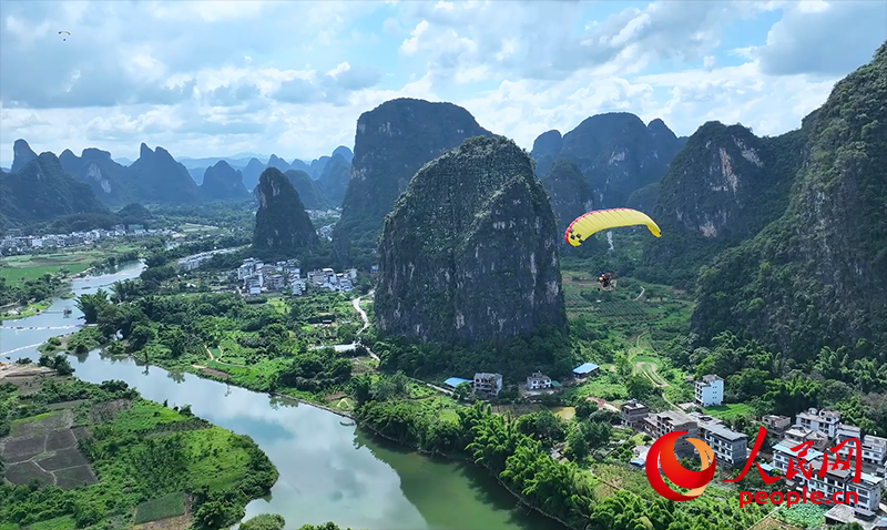 游客乘坐动力滑翔伞看阳朔的山水美景。.png